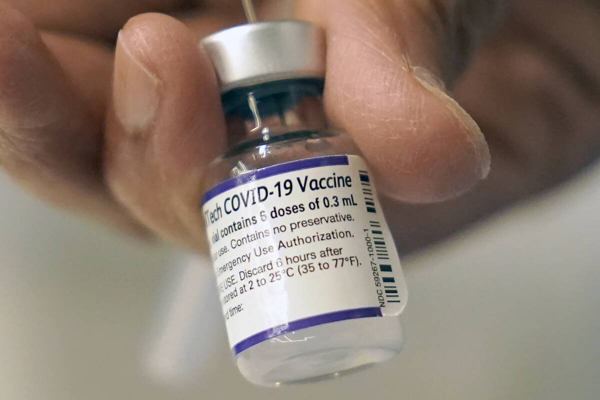 A doctor loads a dose of Pfizer COVID-19 vaccine into a syringe, Thursday, Dec. 2, 2021, at a m ...