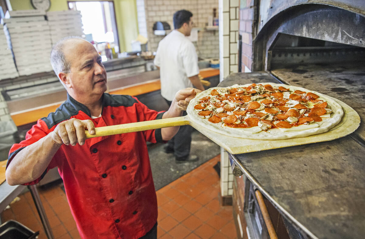 Chef/co-owner John Arena slides an Olde New York specialty pizza in the oven for seven minutes ...