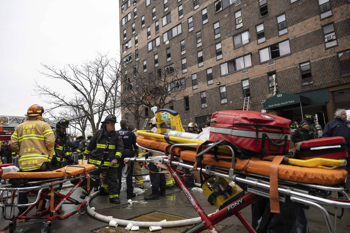 Firefighters work outside an apartment building after a fire in the Bronx, Sunday, Jan. 9, 2022 ...