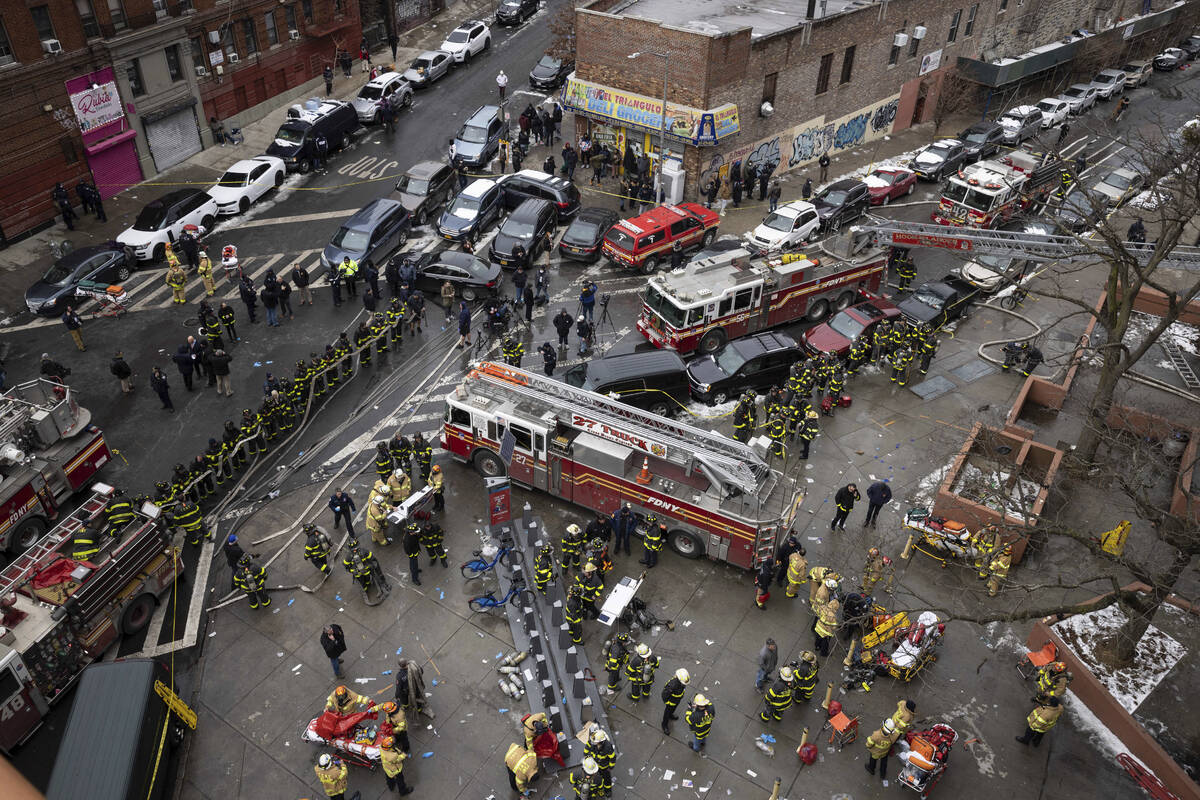 Firefighters work outside an apartment building after a fire in the Bronx, Sunday, Jan. 9, 2022 ...