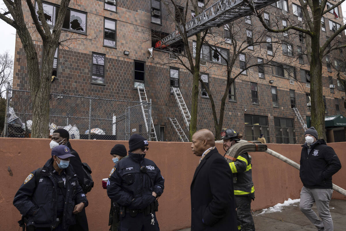 New York City Mayor Eric Adams, third right, walks by an apartment building where a deadly fire ...