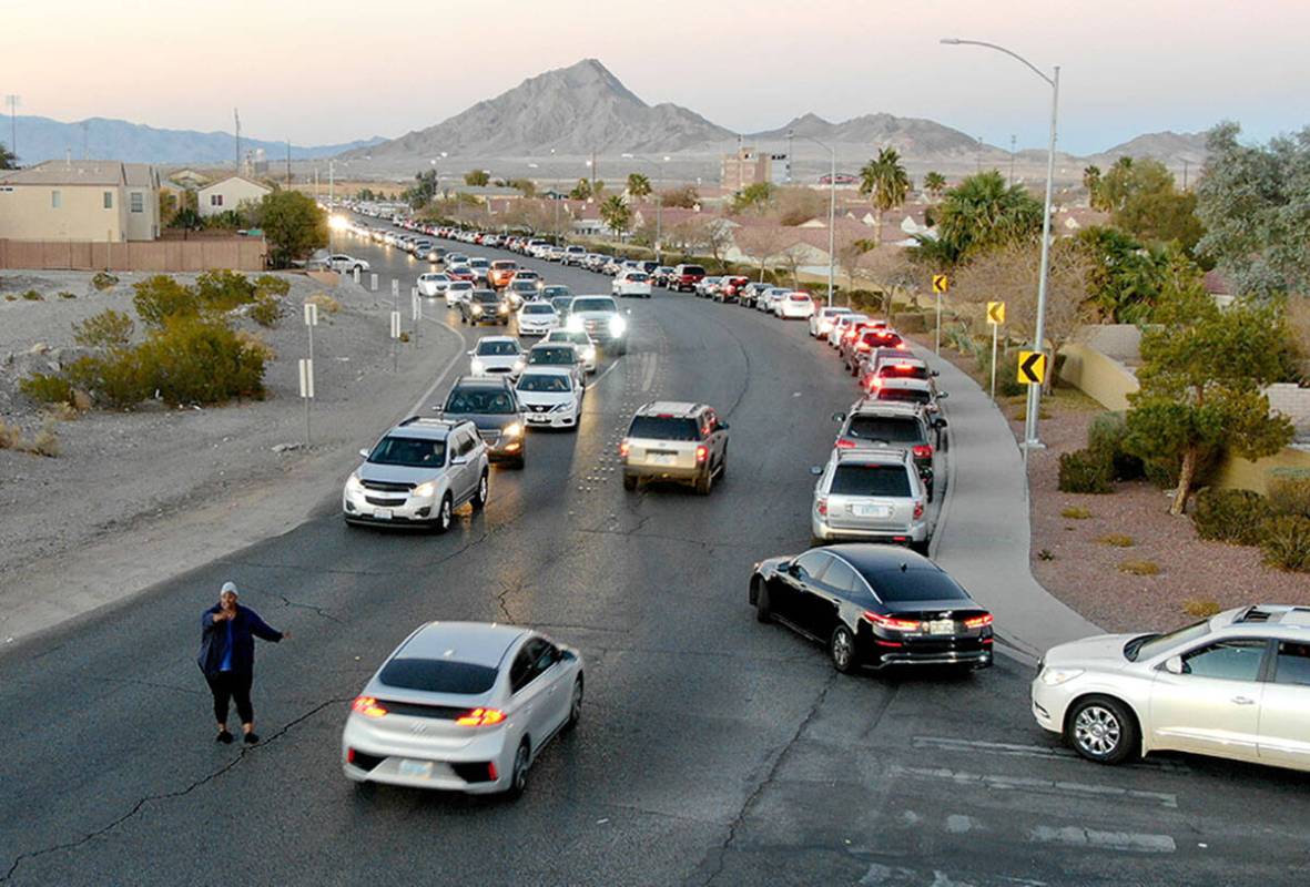 T'onna John helps direct traffic as hundreds of cars line up for the drive-thru COVID testing s ...