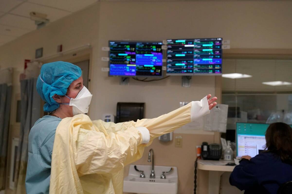 A nurse suits up with protective gear before entering a patient's room at the COVID-19 Intensiv ...