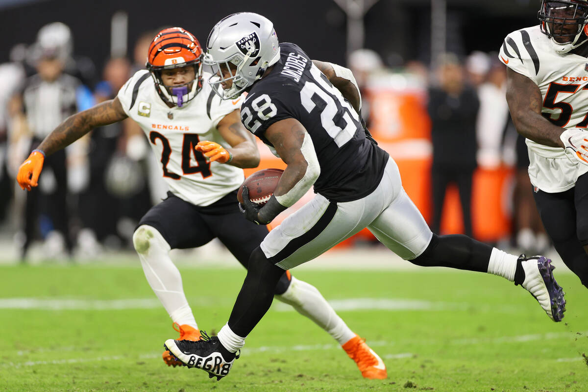 Raiders running back Josh Jacobs (28) runs the ball under pressure from Cincinnati Bengals safe ...