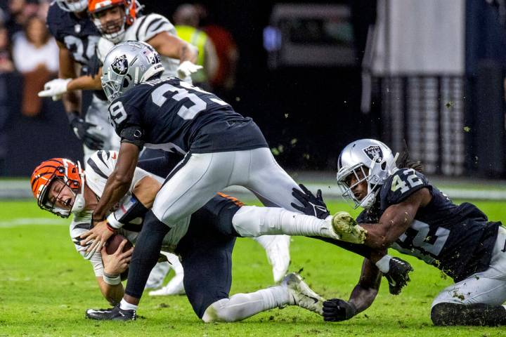 Cincinnati Bengals quarterback Joe Burrow (9) is taken down by Raiders cornerback Nate Hobbs (3 ...