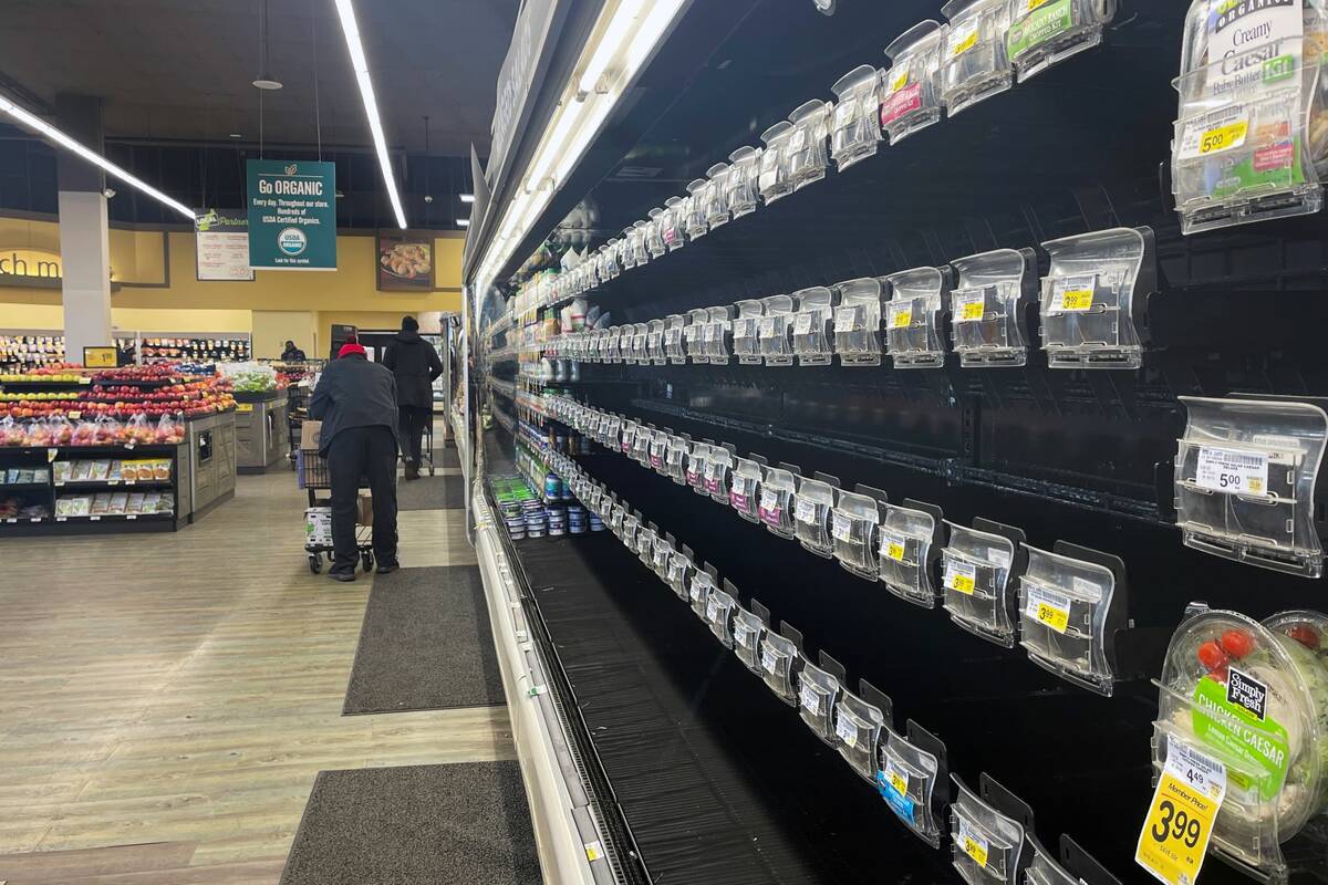 Shoppers walk past empty aisles of produce at a Safeway on Tuesday, Jan. 11, 2022, in Washingto ...