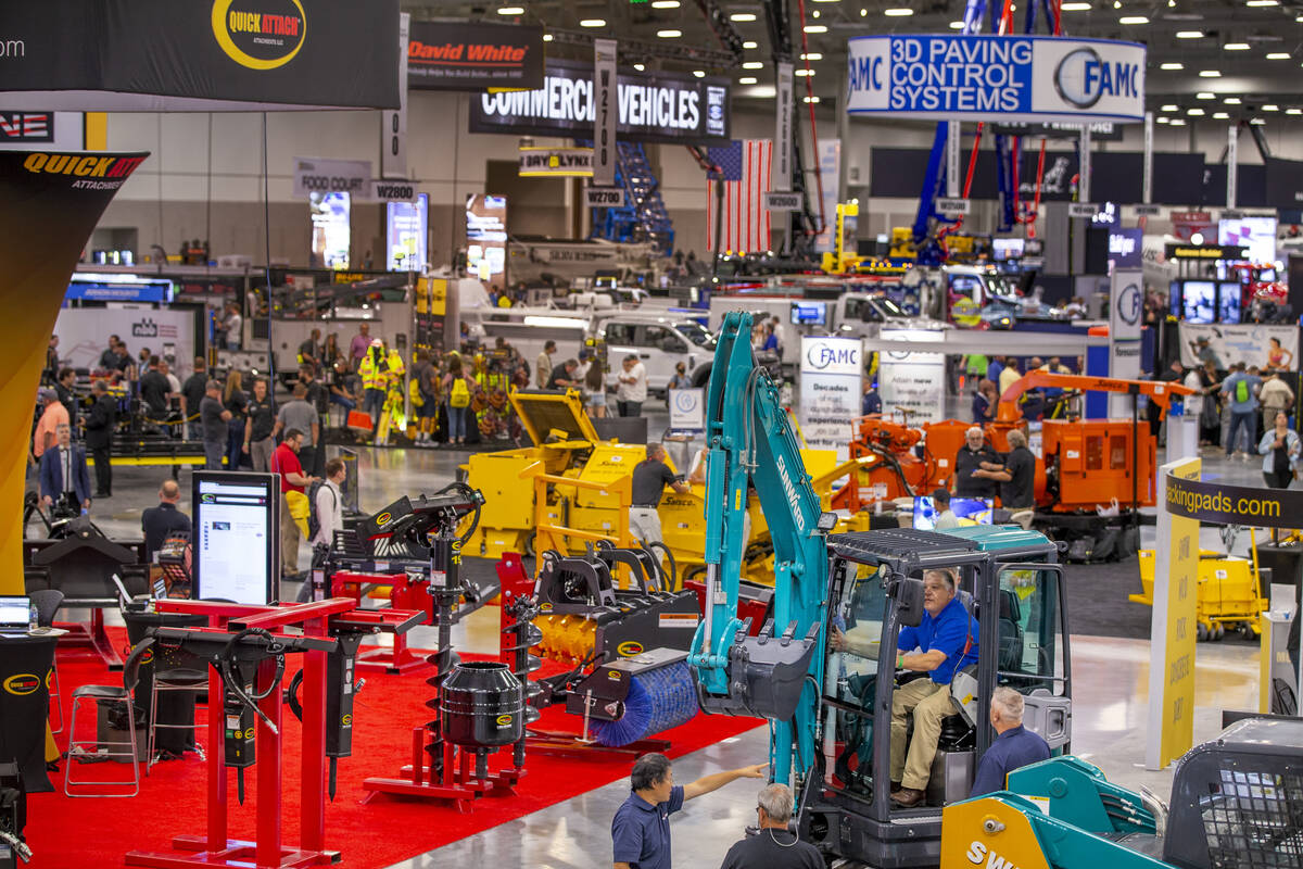 World of Concrete 2021 attendees check out a Sunward excavator at a display about the trade-sho ...