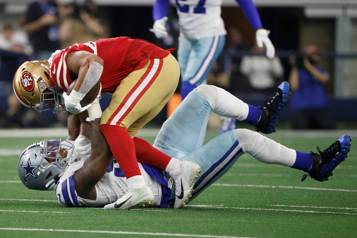 San Francisco 49ers running back Elijah Mitchell, top, is tackled by Dallas Cowboys defensive e ...