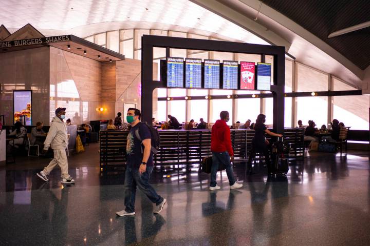 Travelers walk by a display listing departures in Terminal 1 at Harry Reid International Airpor ...