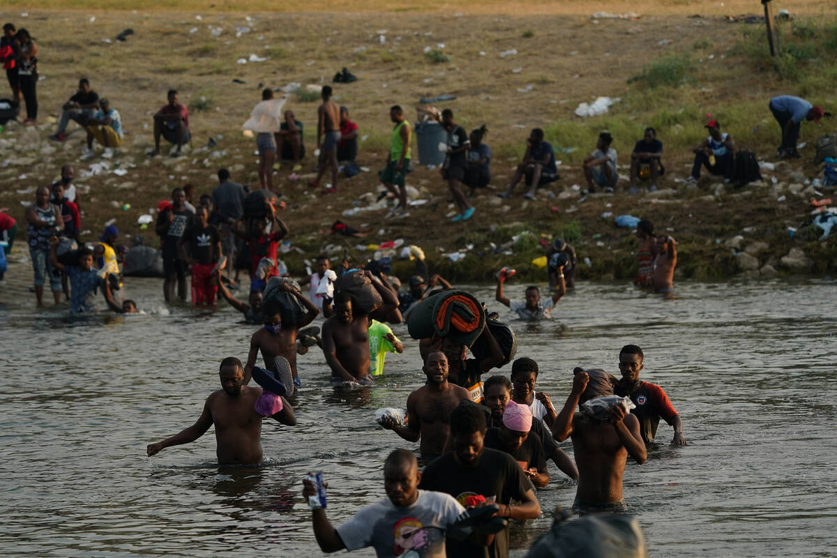 Migrants, many from Haiti, wade across the Rio Grande from Del Rio, Texas, to return to Ciudad ...