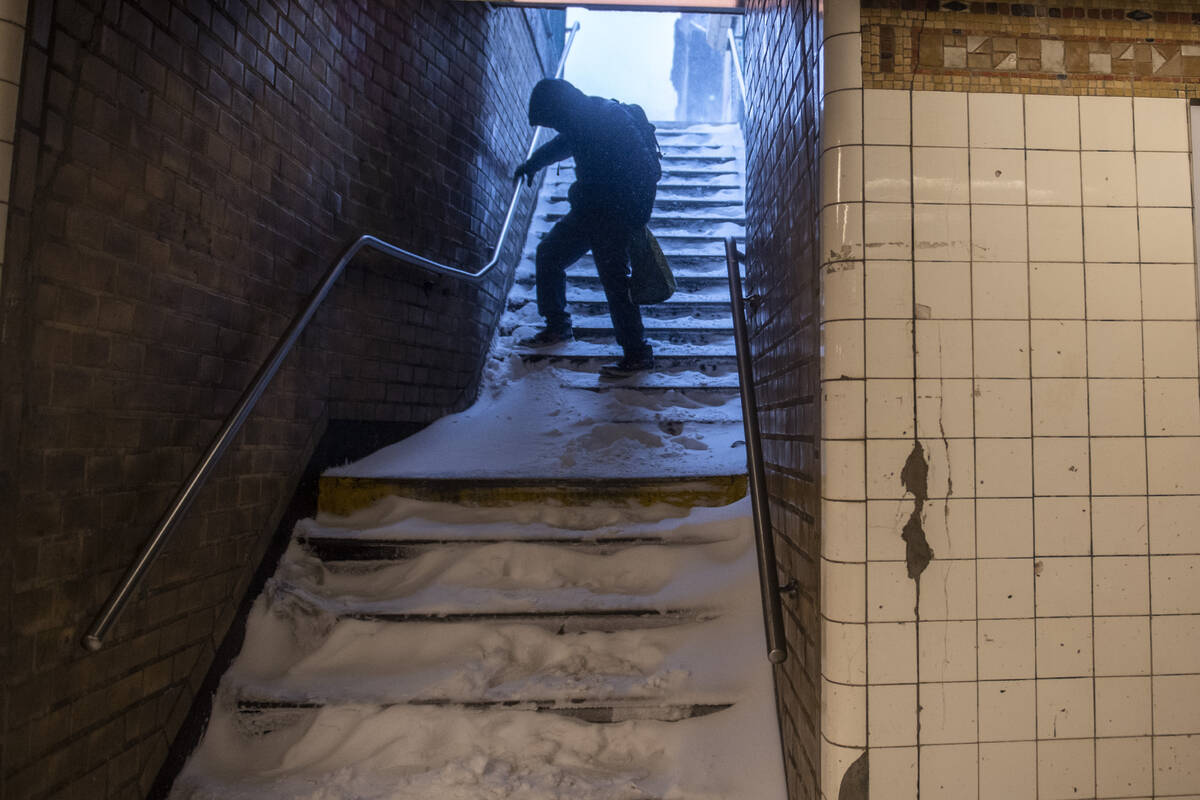 A man carefully walks down the snow covered subway stairs during a snow storm in Bushwick secti ...