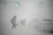 A stranded motorist, at right, gets help shoveling out their car from a passerby with a shovel ...