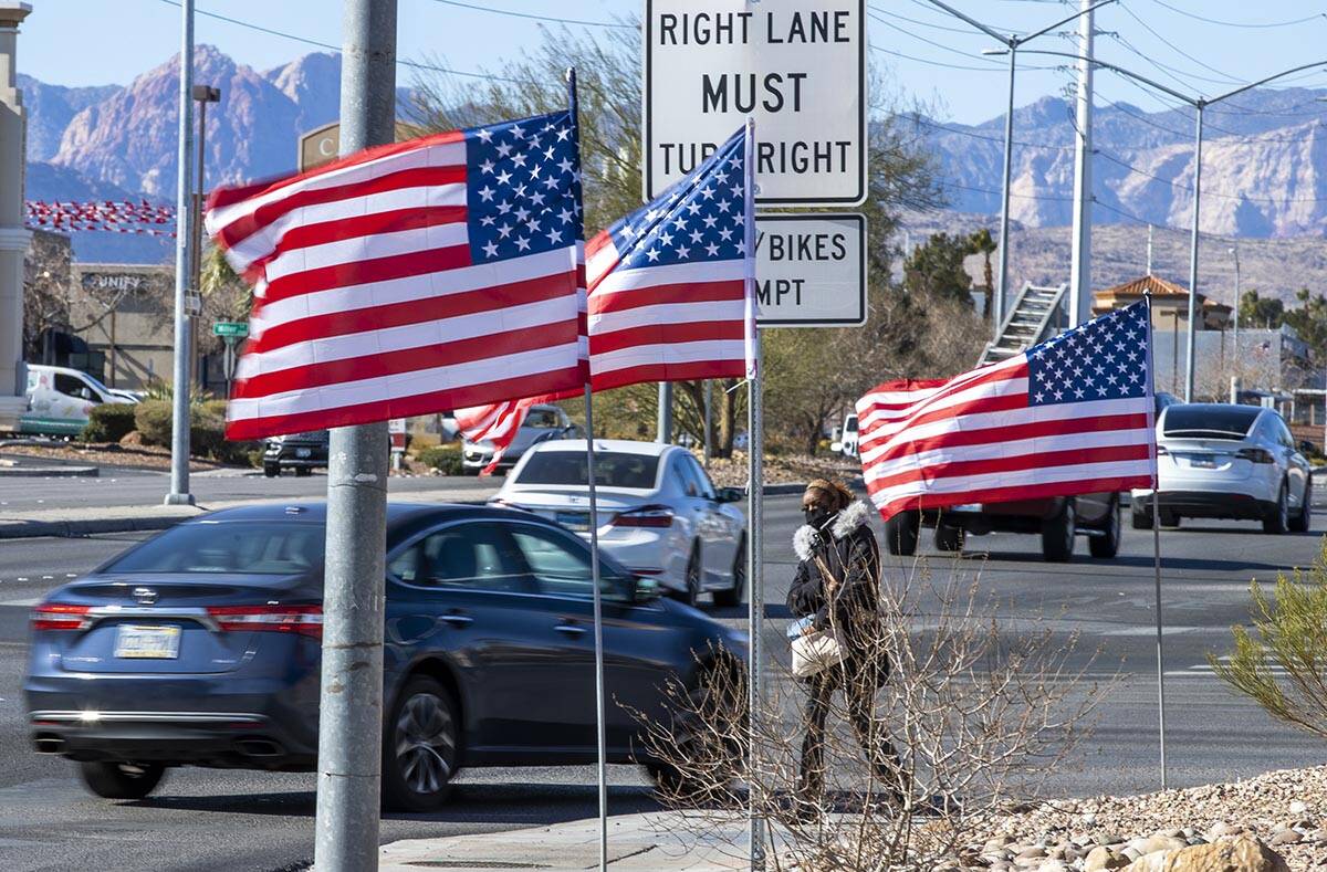 Juanesha Bivens walks along West Sahara Avenue as American flags flutter in the wind on Tuesday ...