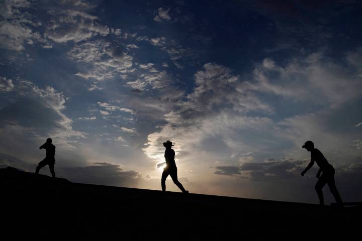 People walk along a trail, July 11, 2021, in Death Valley National Park, Calif. (AP Photo/John ...