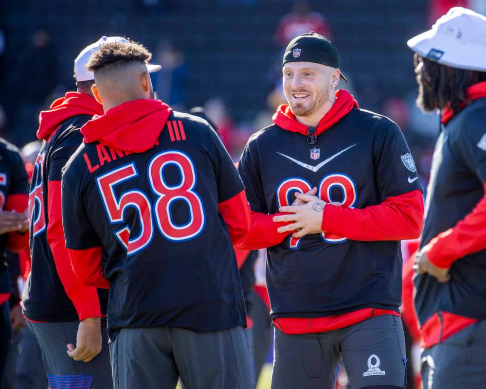 Raiders defensive end Maxx Crosby (98) talks with teammate Tennessee Titans linebacker Harold L ...