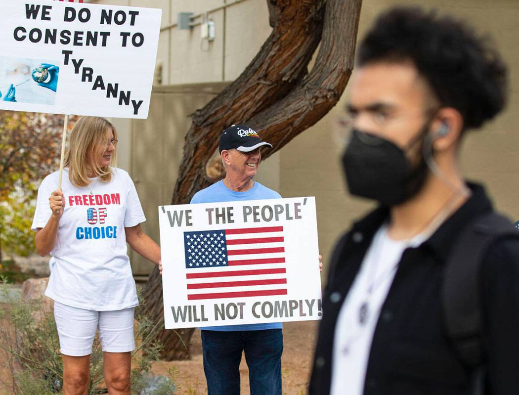 A UNLV student walks past Julie Williams and her husband Terry, both of Henderson, as they prot ...