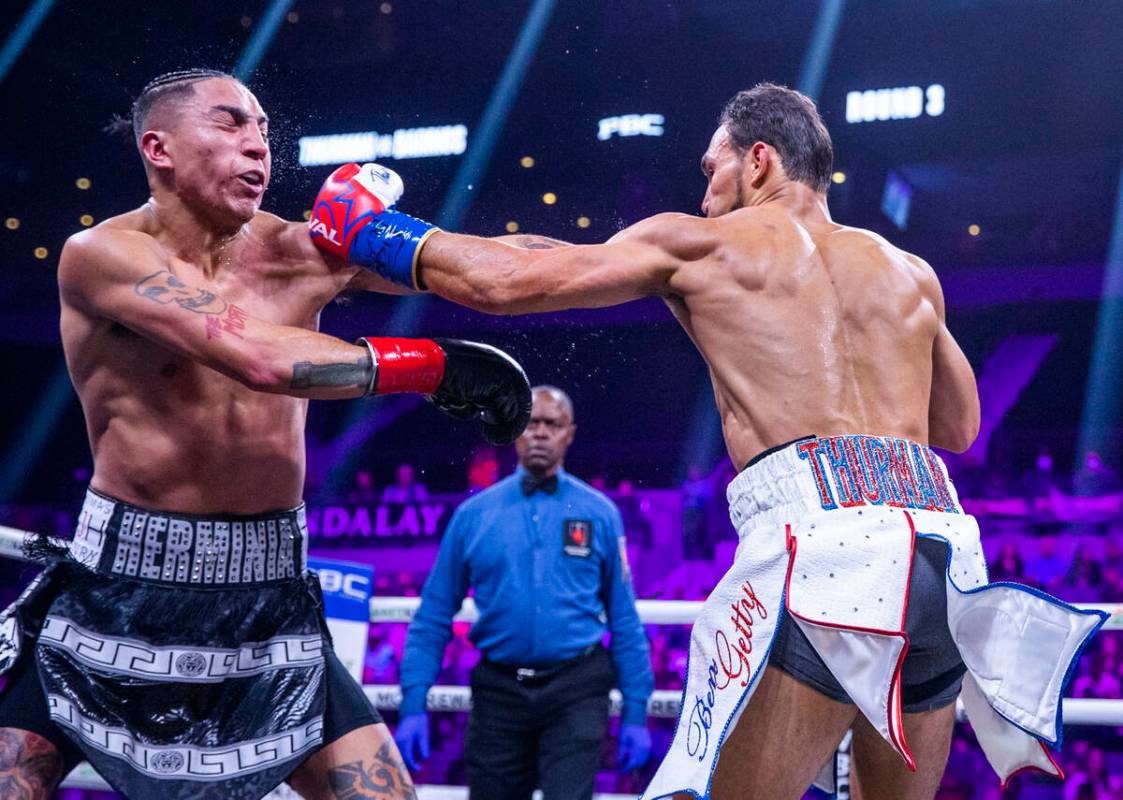 Mario Barrios, left, takes a punch from Keith Thurman during the third round of their Welterwei ...