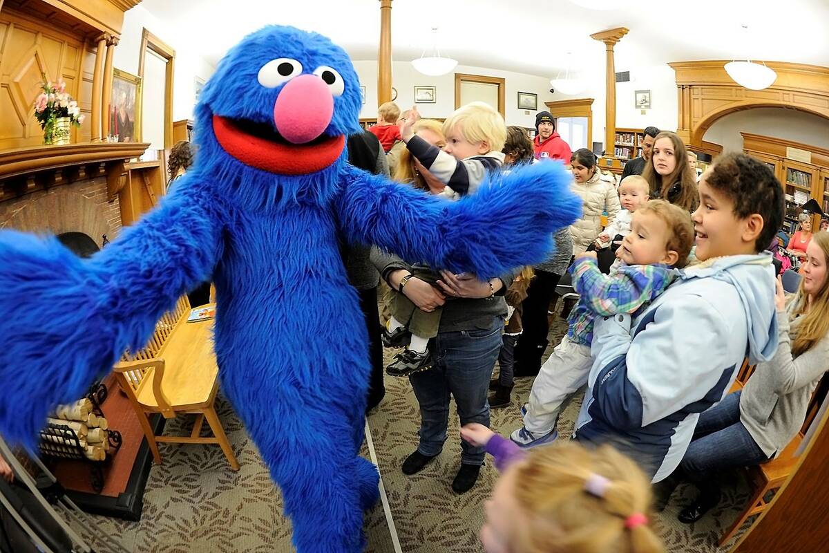 Sesame Street character Grover reaches out to hug children after a visit to the Osterhout Libra ...