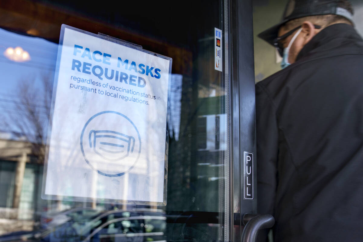 A customer enters a restaurant past a sign posted to the door requiring masks Wednesday, Feb. 9 ...