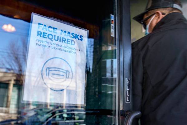A customer enters a restaurant past a sign posted to the door requiring masks Wednesday, Feb. 9 ...