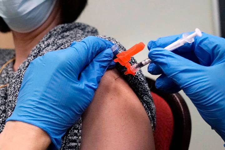 FILE - A woman receives a COVID-19 vaccine injection by a pharmacist at a clinic in Lawrence, M ...