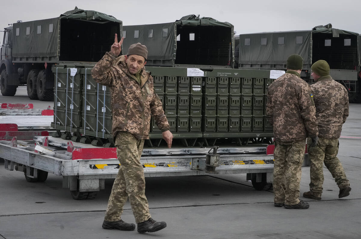 An Ukrainian serviceman flashes the V for victory sign during unpacking shipment of military ai ...