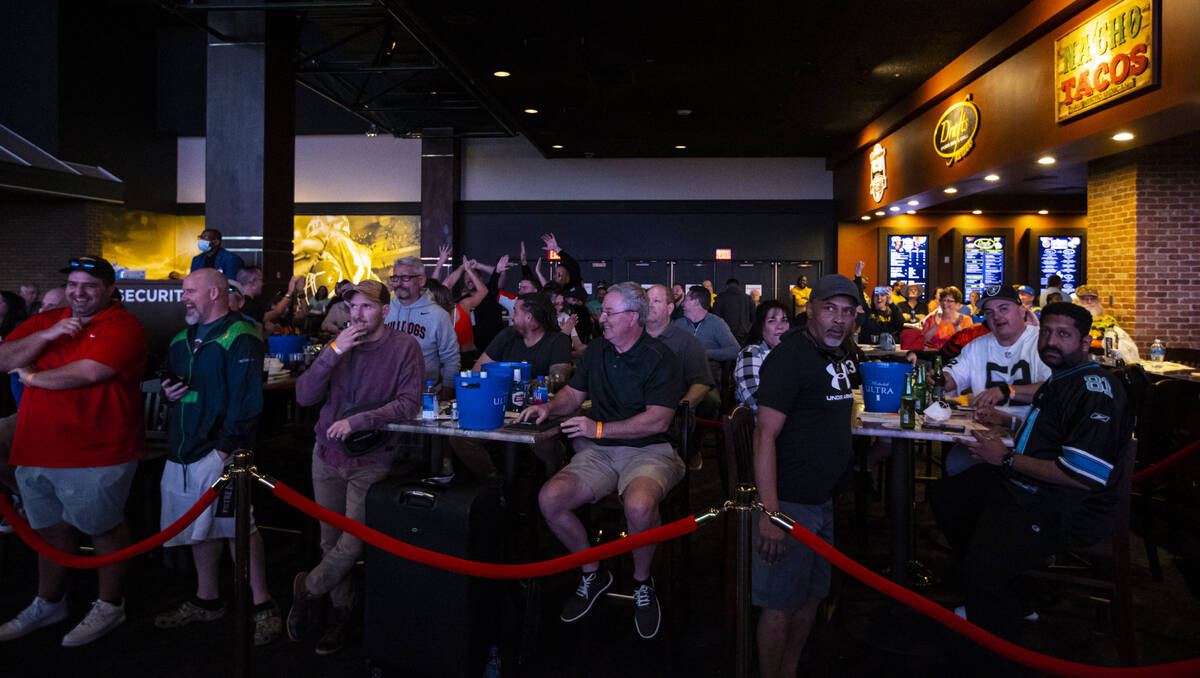 Attendees cheer after the coin toss at the start of the Super Bowl watch party at the Westgate ...