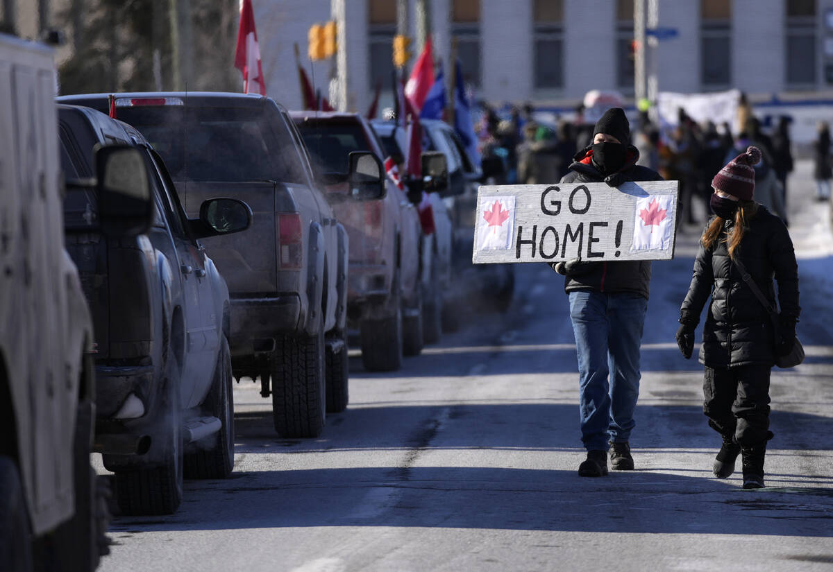 A resident holds a sign towards protesters as they participate in a counter protest to stop veh ...