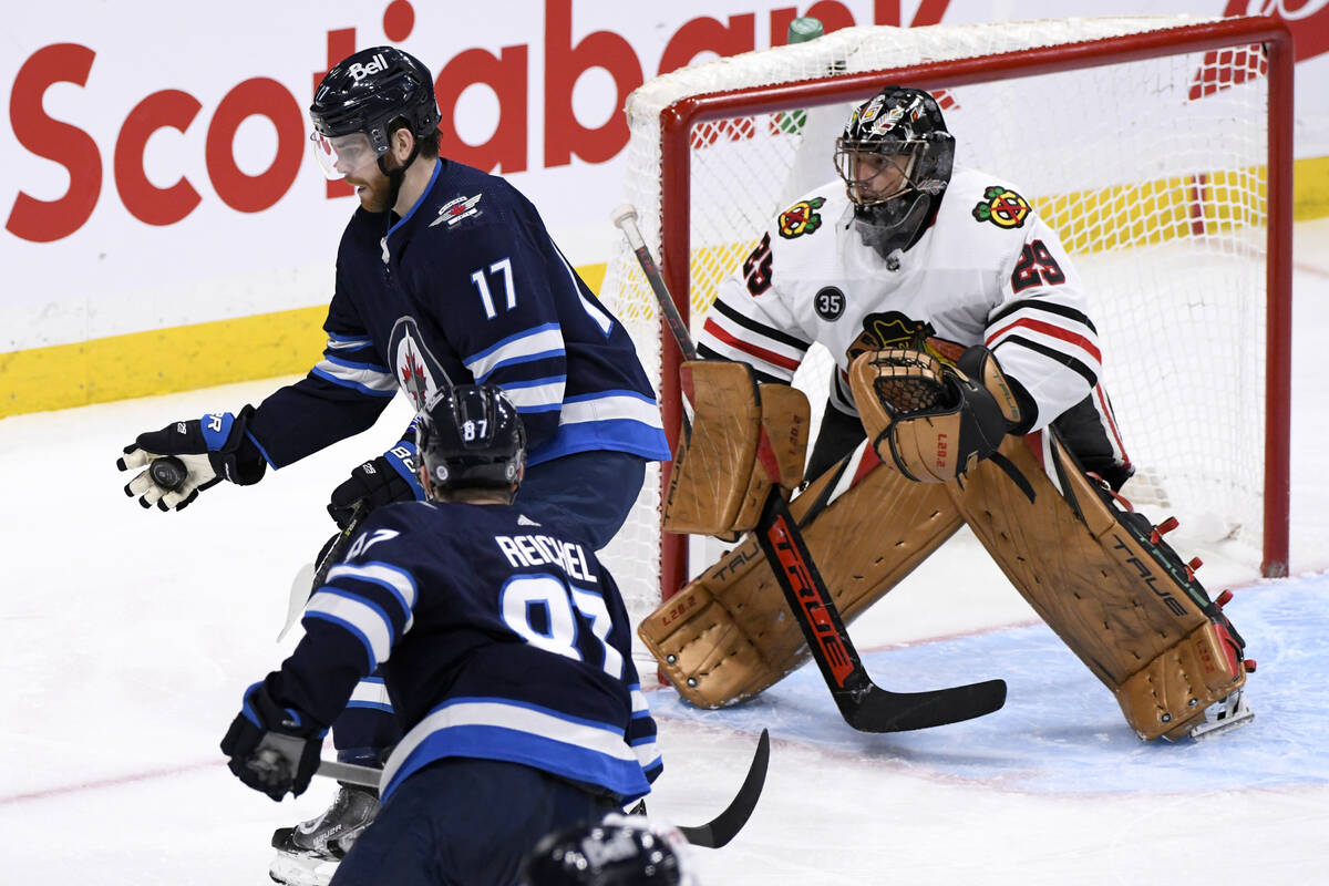 Winnipeg Jets' Adam Lowry (17) knocks down the puck in front of Chicago Blackhawks goaltender M ...