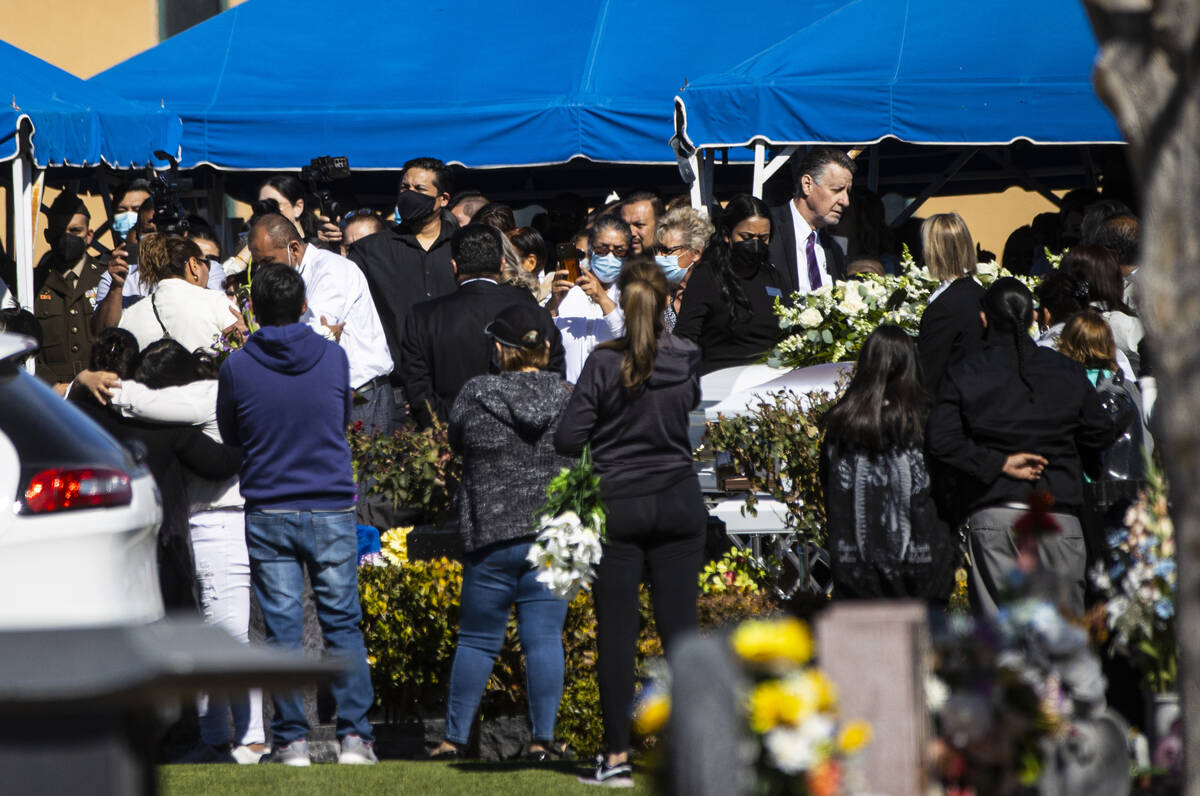 Mourners, left, embrace near caskets during the service and burial of members of the Zacarias f ...