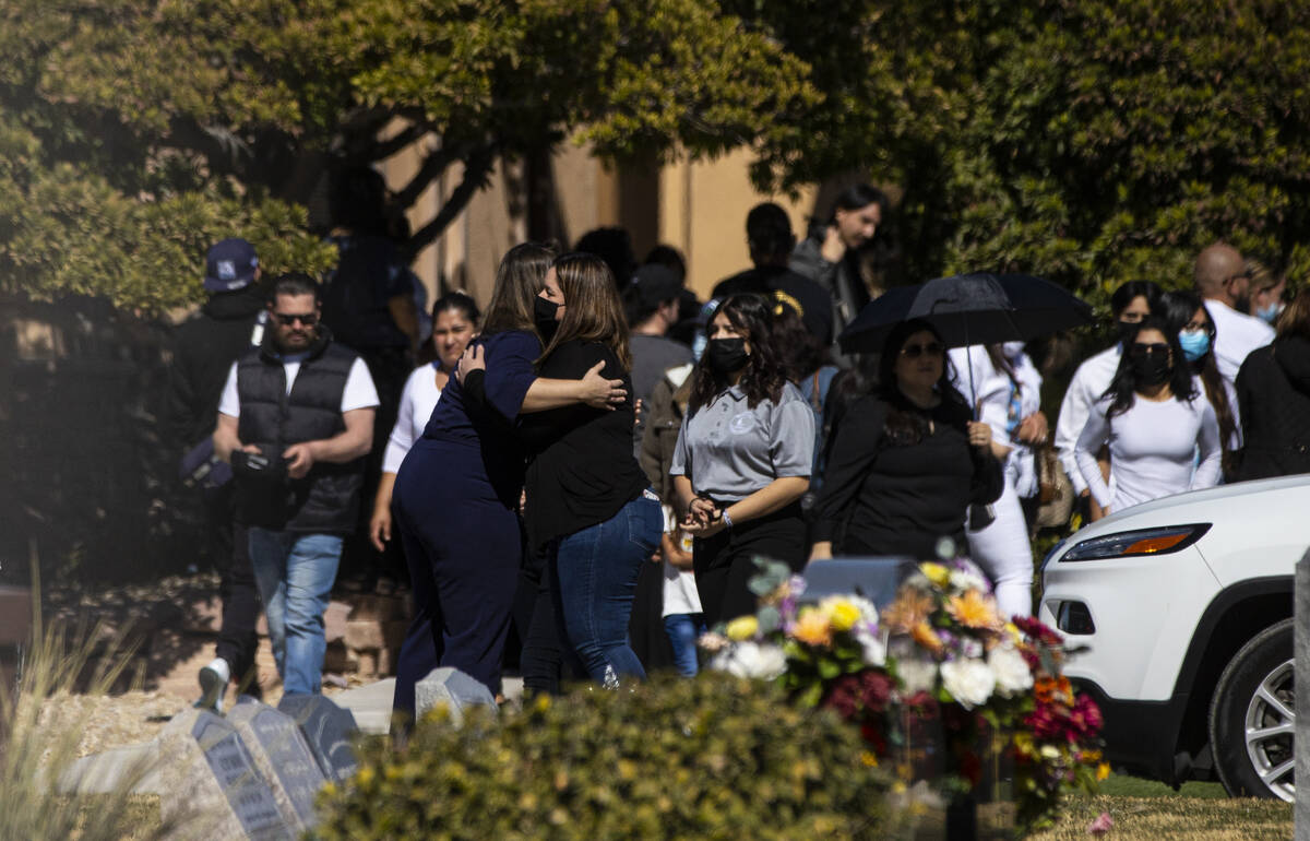 People embrace during the service and burial of members of the Zacarias family who were killed ...