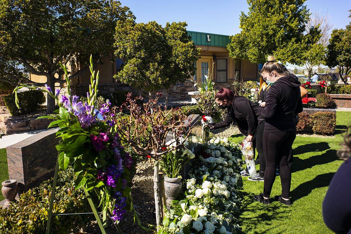 Mourners leave floral arrangements at the burial site of the five Zacarias family members that ...