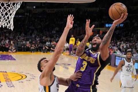 Los Angeles Lakers forward Anthony Davis, center, shoots as Utah Jazz center Rudy Gobert defend ...
