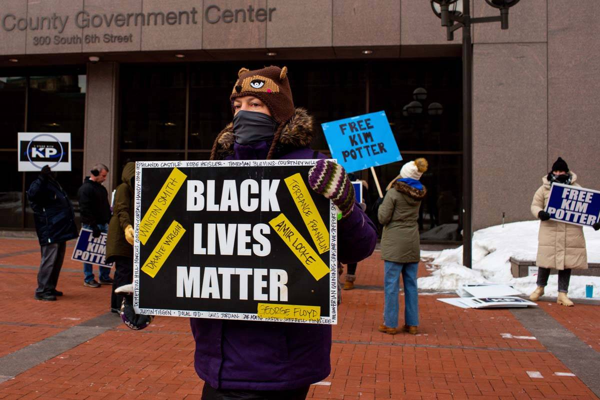 A demonstrator carries a Black Lives Matter sign in front of a group of demonstrators calling f ...