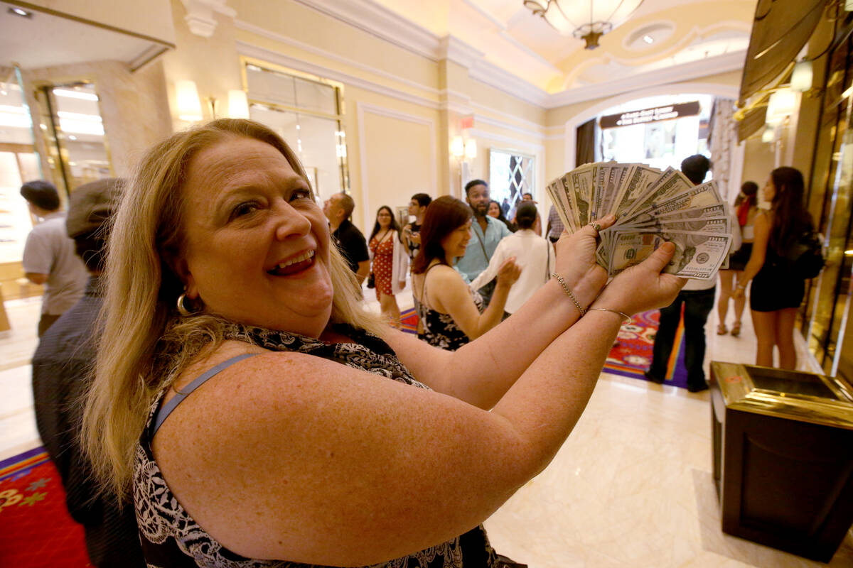 Tammy Akusis, of Abington, Mass., shows her winnings on opening day of the $2.6 billion Encore ...