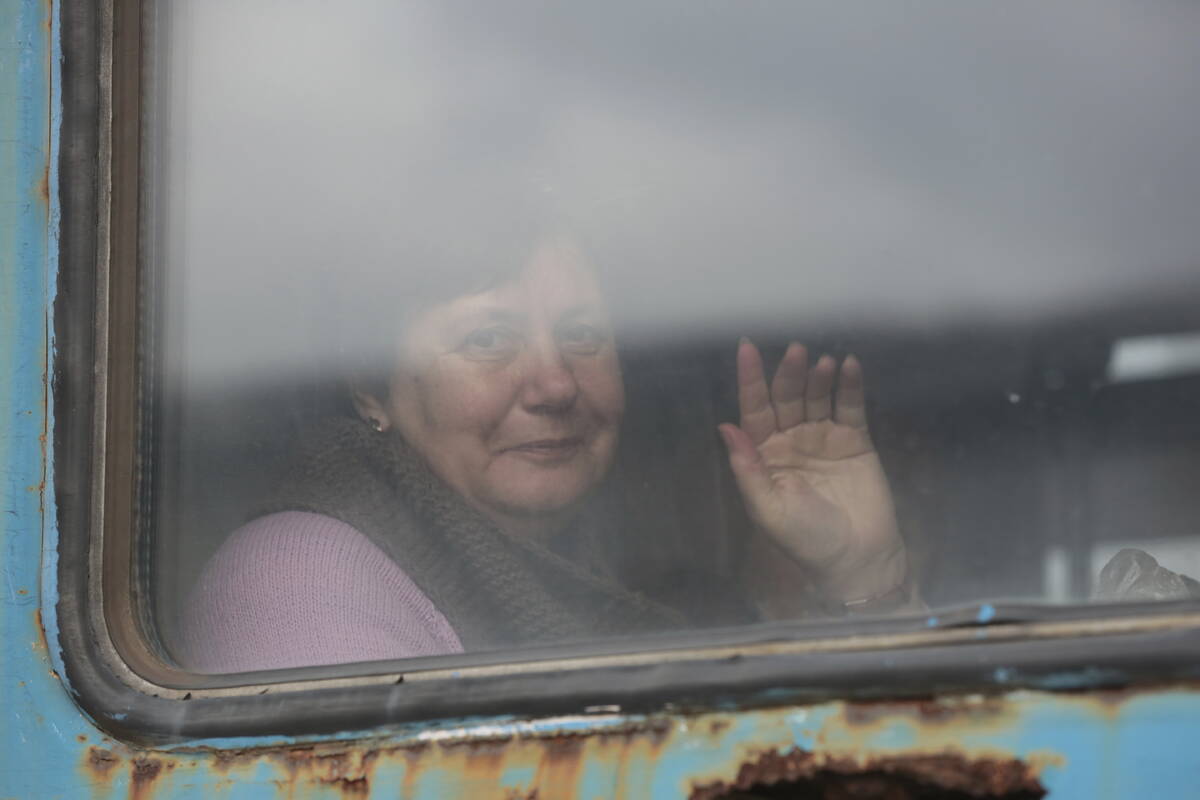 A woman waves from a train carriage to be evacuated to Russia, at the railway station in Debalt ...