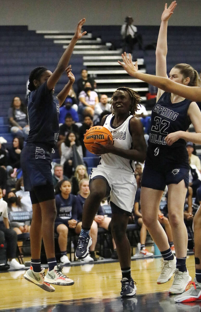 Centennial High School's Mary McMorris (4), center, goes to the basket as Spring Valley High Sc ...