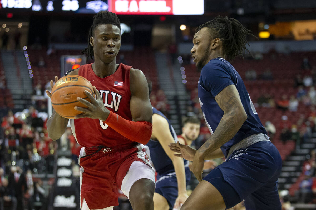 UNLV Rebels forward Victor Iwuakor (0) drives around Nevada Wolf Pack forward Tre Coleman (14) ...