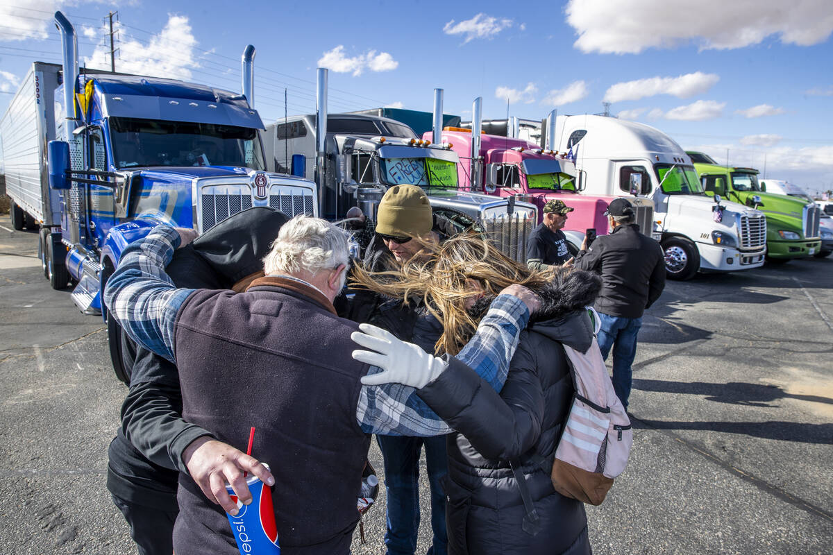 Attendees hold a prayer circle beside semi trucks arriving for The People’s Convoy stagi ...