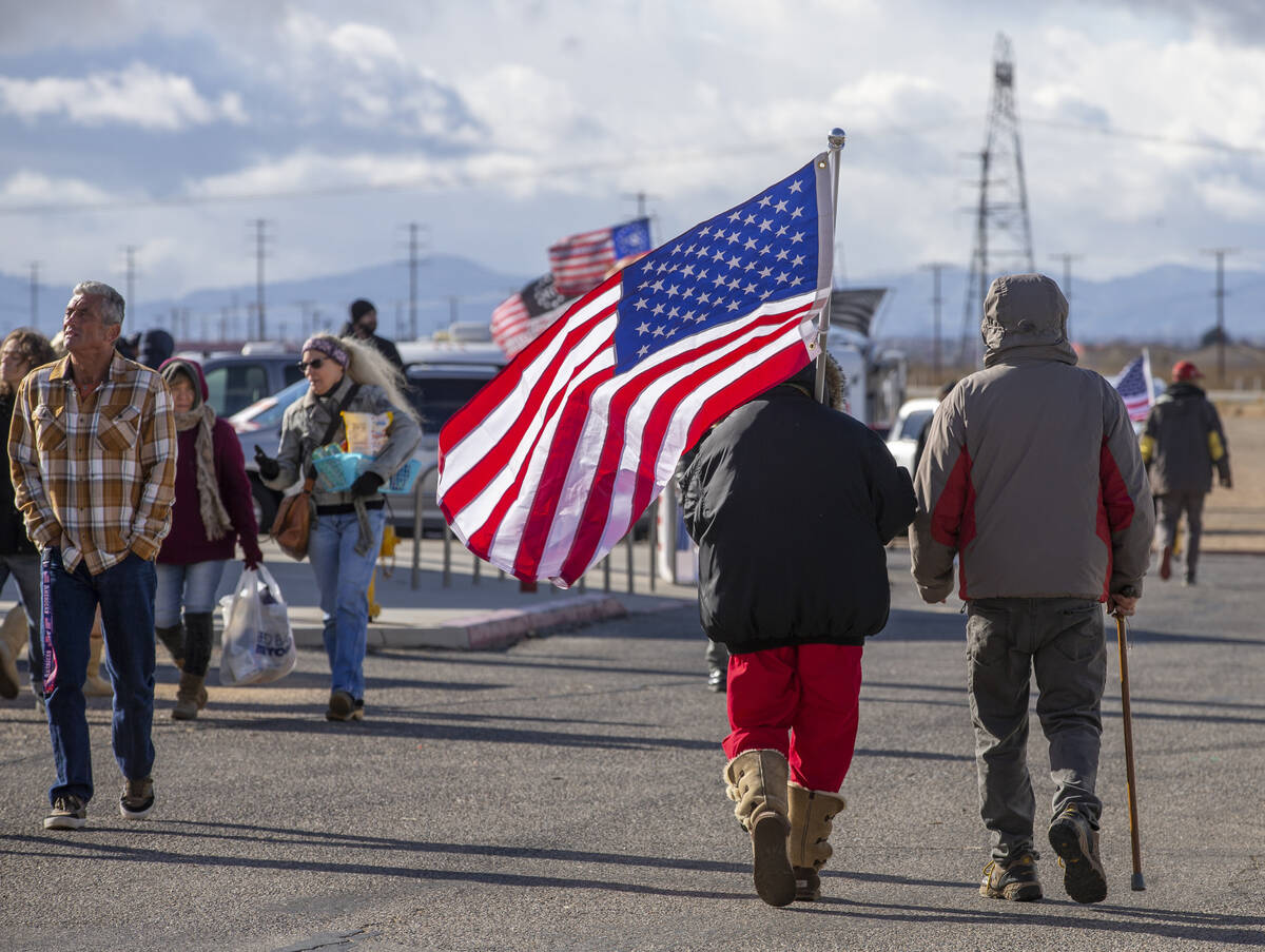 Attendees carry flags and make their way along during a departure event for The People’s ...