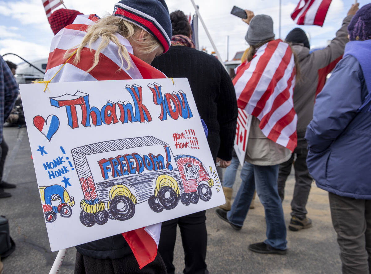 An attendee holds her sign during a departure event for The People’s Convoy at Adelanto ...