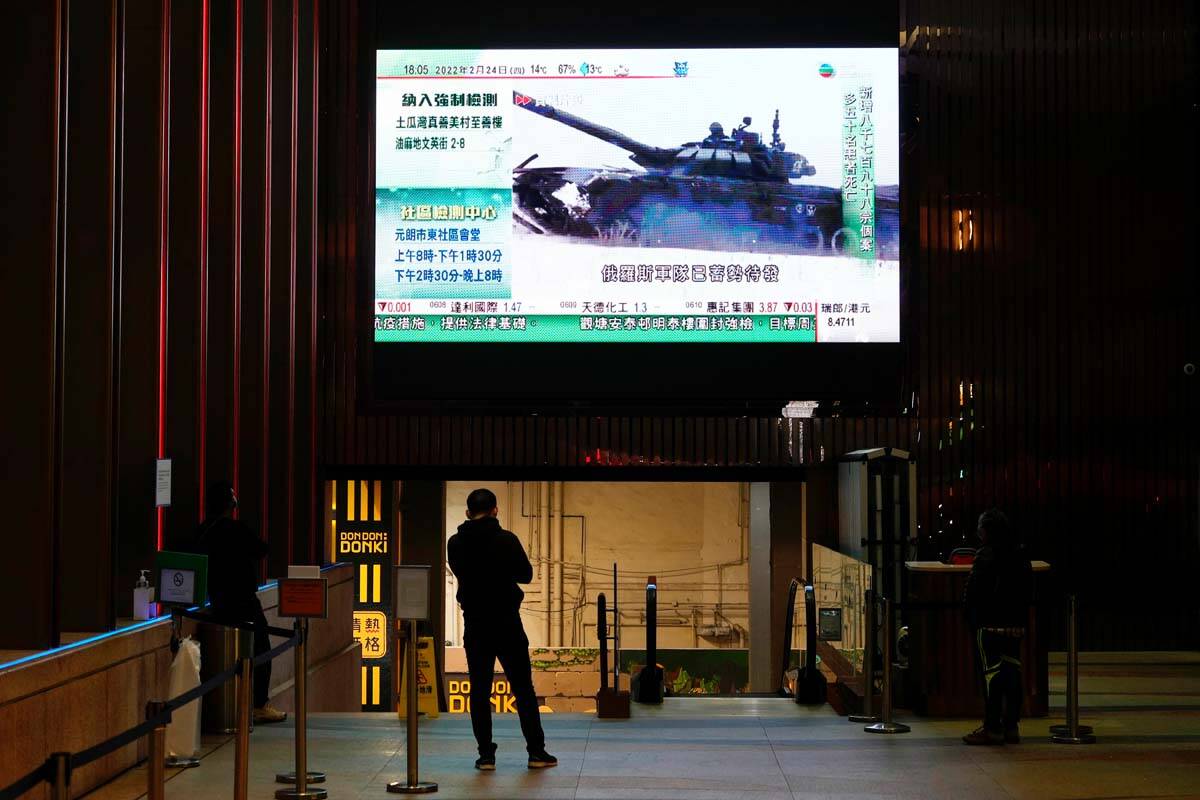 A man watches a huge TV screen broadcasting the news of Russian troops that have launched their ...