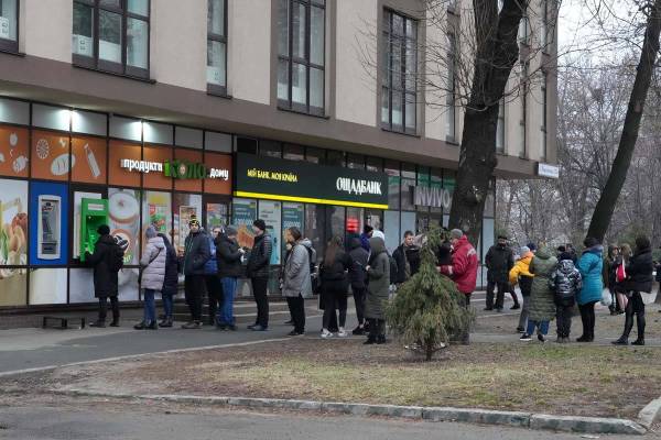 People line up to withdraw their money from an ATM in Kyiv, Ukraine, Thursday, Feb. 24, 2022. U ...