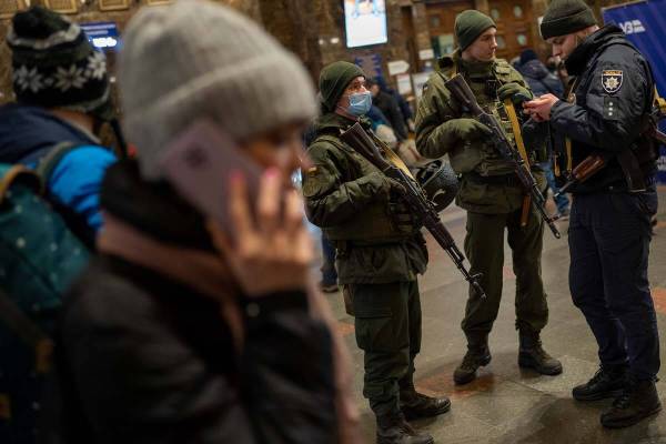 Ukrainian soldiers stand guard as people try to leave at the Kyiv train station, Ukraine, Thurs ...