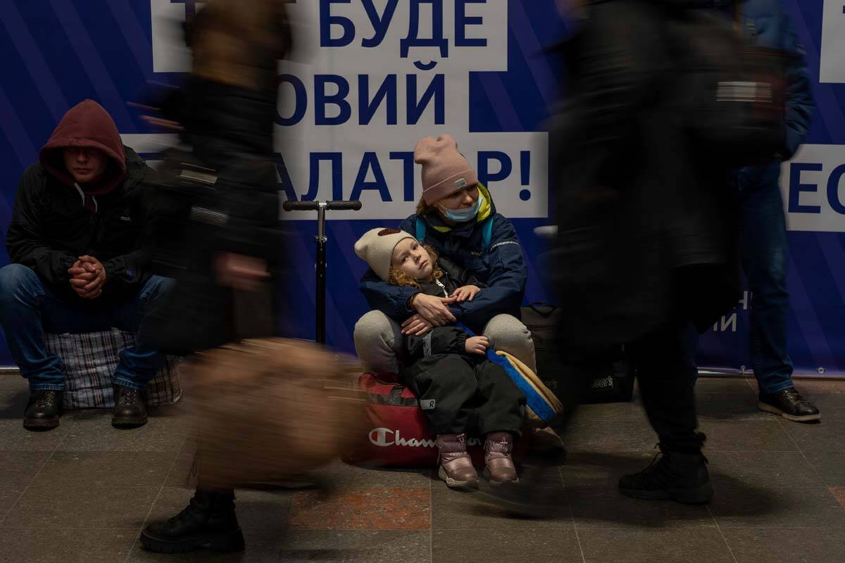 A woman with her daughter waits for a train as they try to leave at the Kyiv train station, Ukr ...
