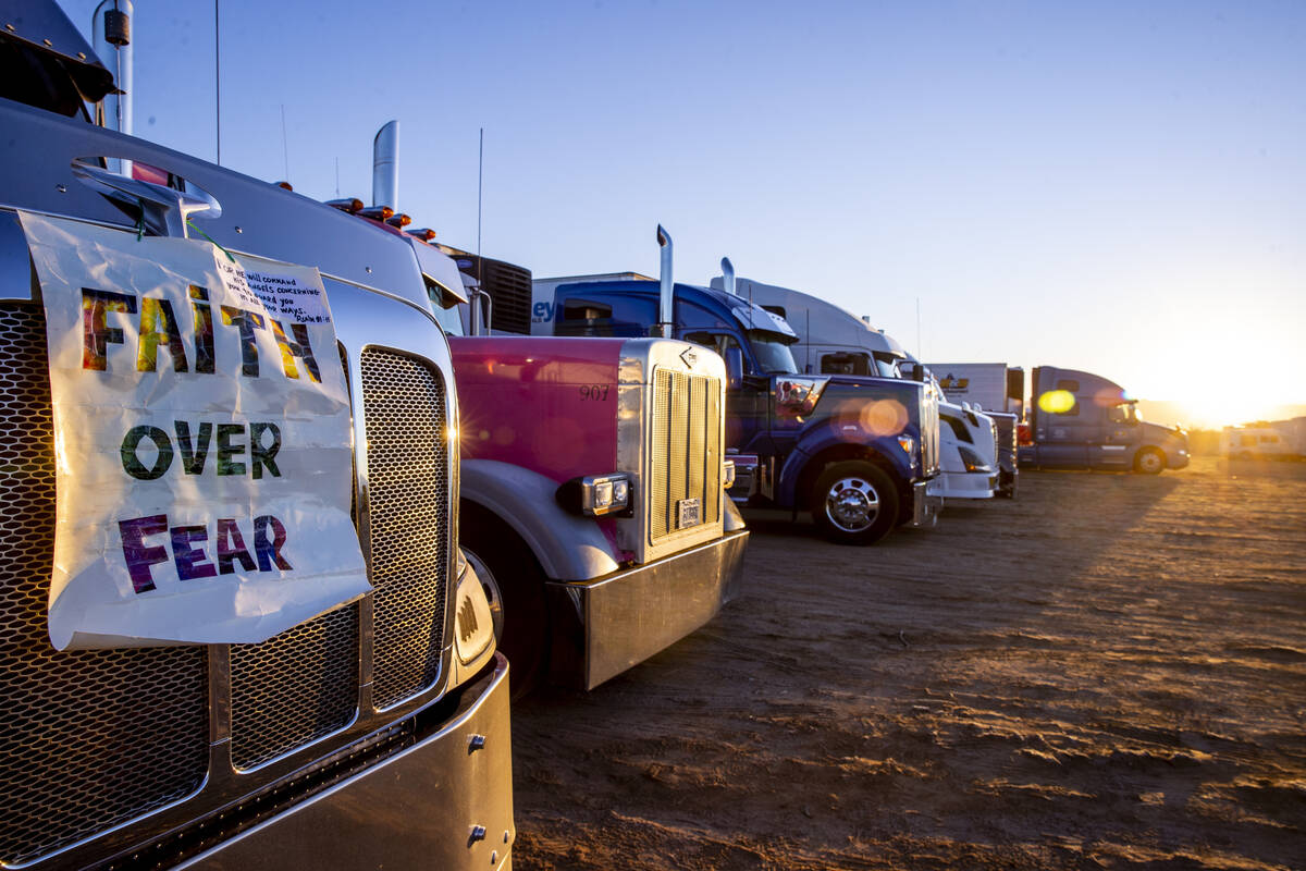 Truckers parked in a back lot for The People’s Convoy parked for the night greet the sun ...