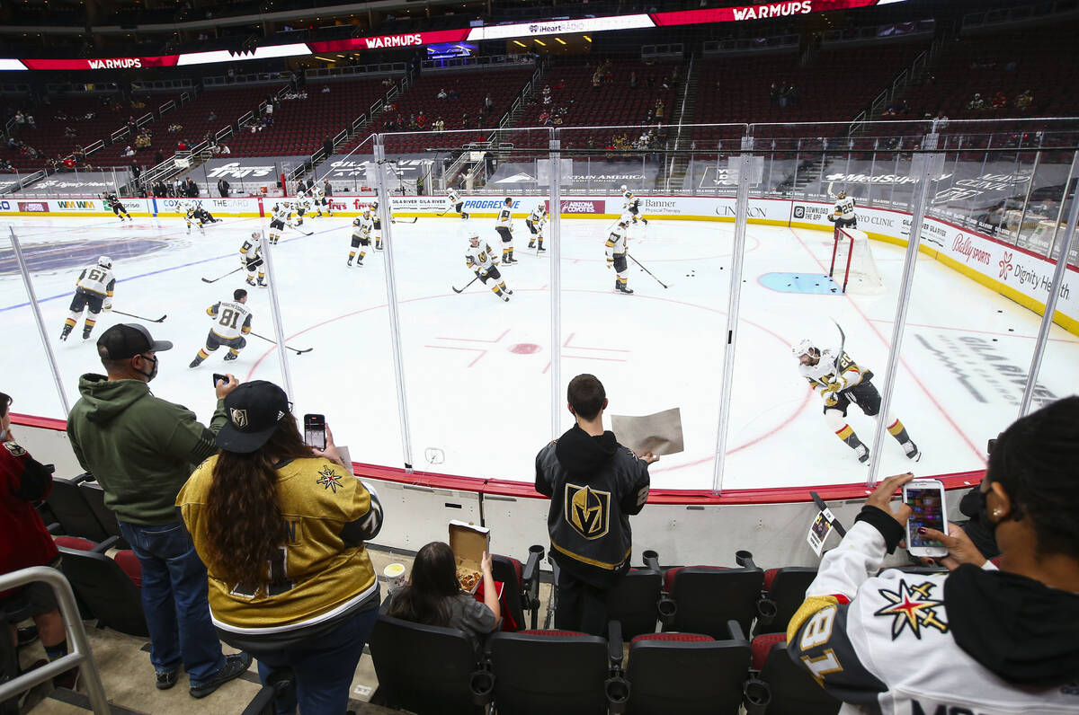 Golden Knights fans watch as players warm up before an NHL hockey game against the Arizona Coyo ...