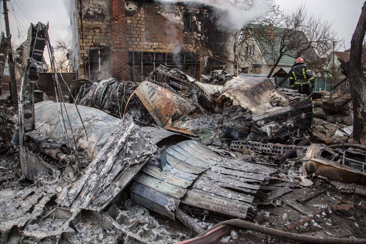 A Ukrainian firefighter walks between at fragments of a downed aircraft seen in in Kyiv, Ukrain ...