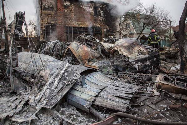 A Ukrainian firefighter walks between at fragments of a downed aircraft seen in in Kyiv, Ukrain ...