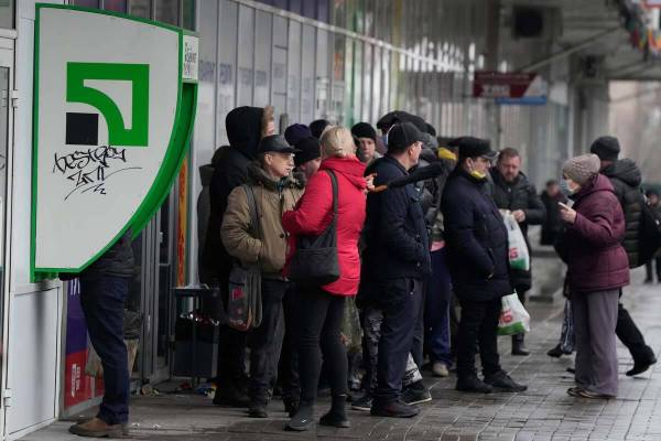 People line up to withdraw their money from an ATM in Zaporizhzhia, Ukraine, Friday, Feb. 25, 2 ...